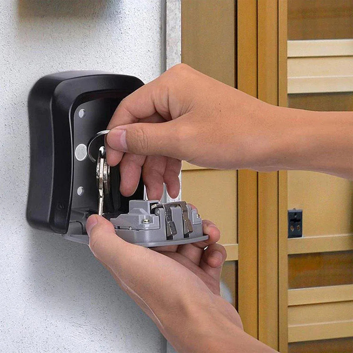 Person inserting a key into a black wall-mounted lock mechanism.