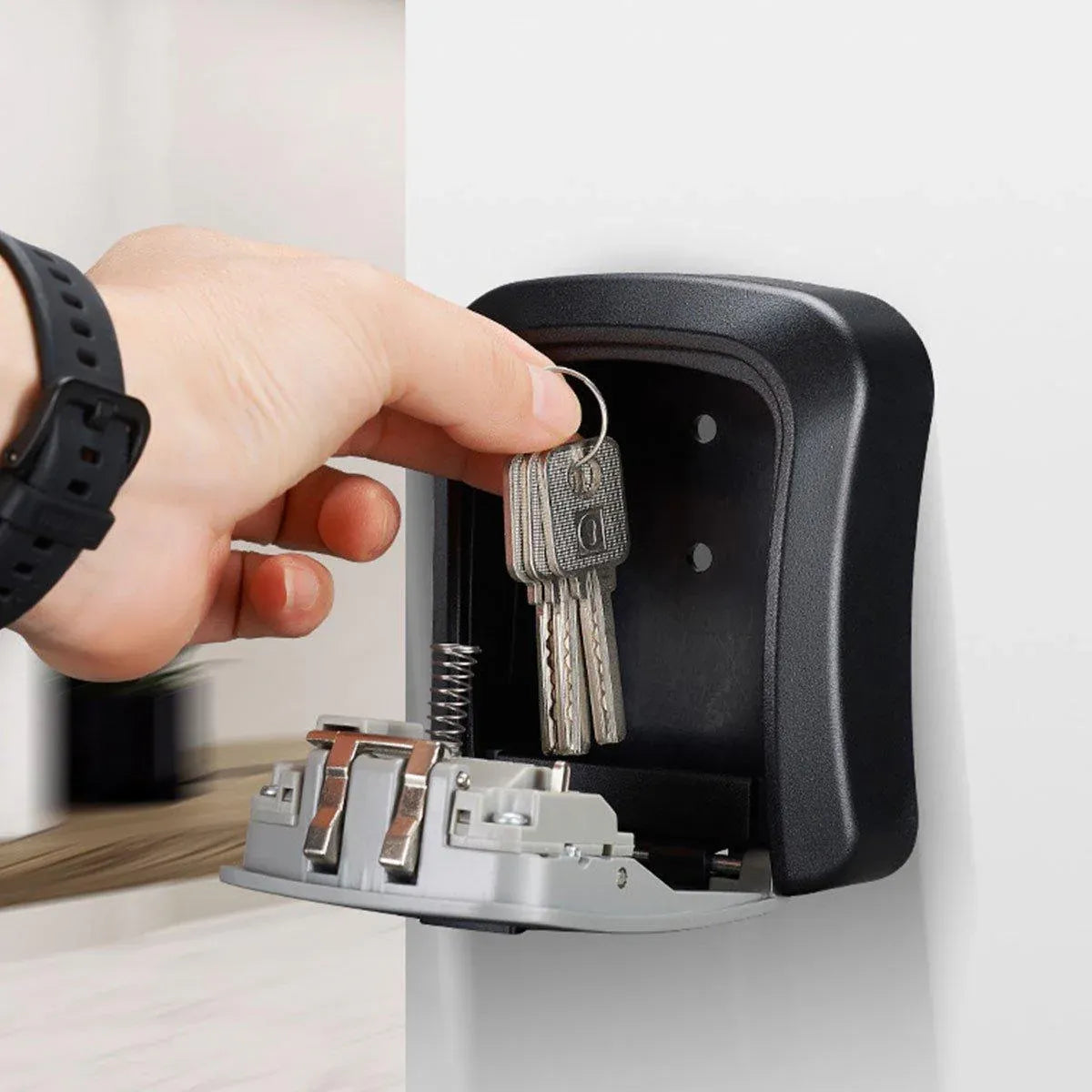 Hand inserting keys into a key storage device mounted on a wall.