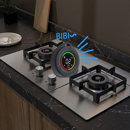 Portable carbon monoxide detector monitoring gas levels beside a kitchen cooktop