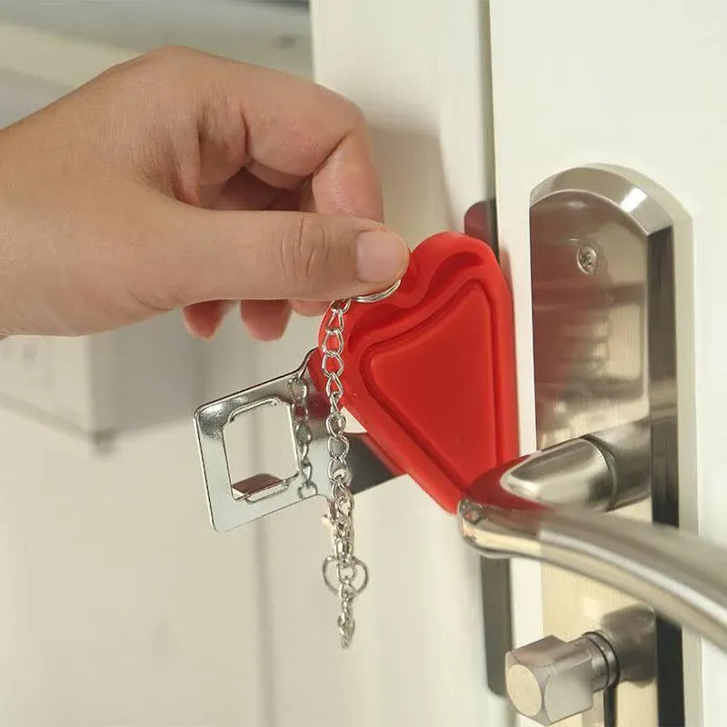 Red heart-shaped portable hotel door lock attached to a door handle with keys hanging from it.