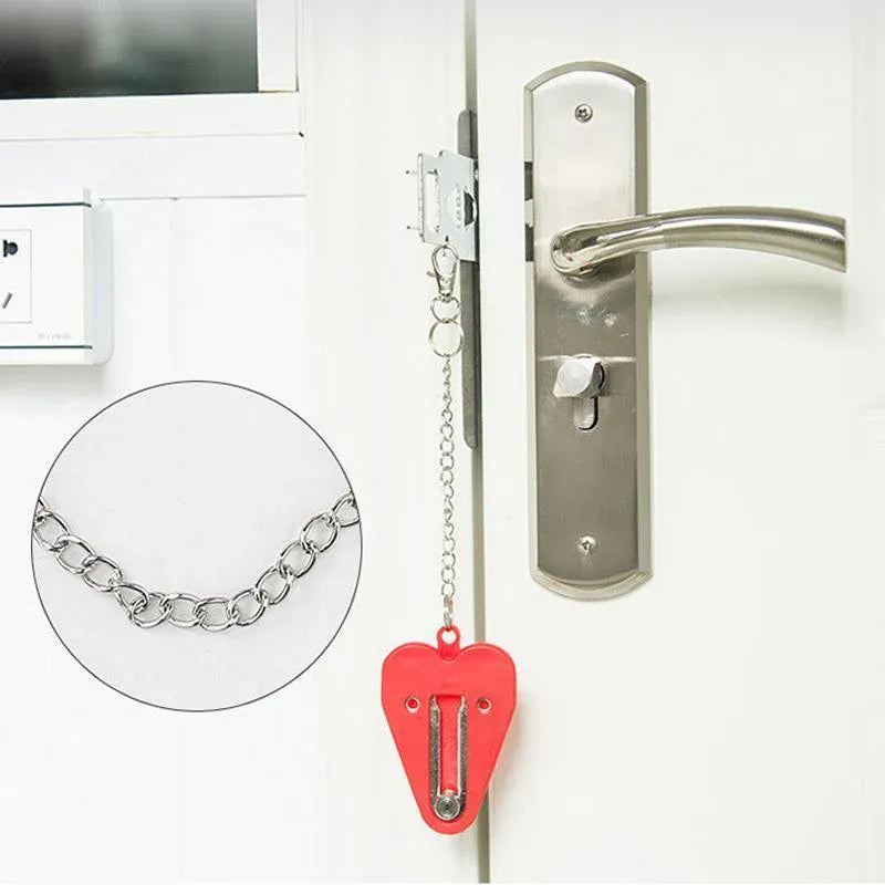 Door handle with a security chain and red heart-shaped portable door lock on a white door.