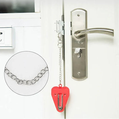 Door handle with a security chain and red heart-shaped portable door lock on a white door.